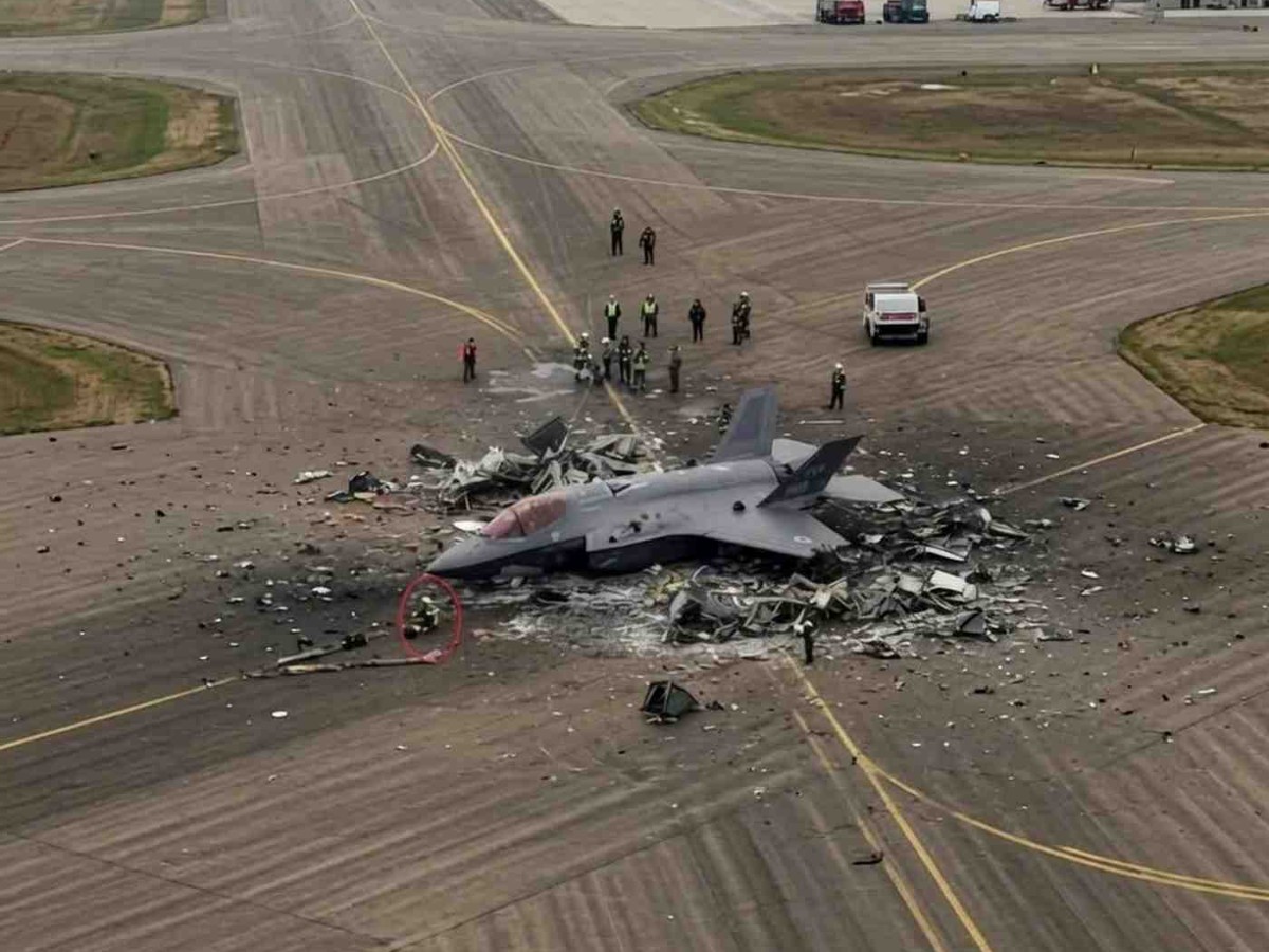 Wreckage of EA-18G Growler crash site on airport runway with emergency response personnel and vehicles present