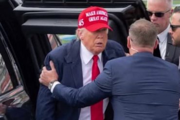 Political figure in red hat surrounded by security detail, subject of Trump misinformation false claim discussions